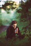 man pray sit sitting praying grass field meadow stock photo
