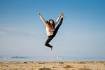 girl jump happy dance sea nature beach fun stock photo